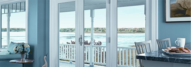 hinged-patio-door hinged french doors opening to a deck with view of a beach