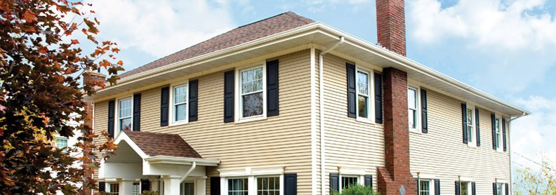 Milbank home featuring tan stainless steel siding and brick chimney