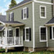 subdued-green home exterior with seamless steel siding, dark gray roofing, white accents and deck, and windows with dark gray shutters